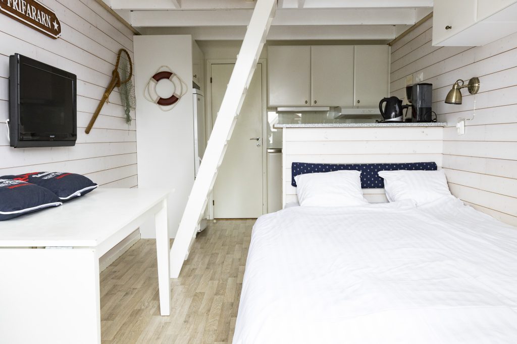 En vit stuga med en dubbelsäng.