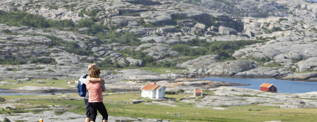 Ett par, som bokat vandringspaket på Ramsvik, tittar ut över hav och klippigt landskap i Ramsvikslandets naturreservat i Bohuslän.