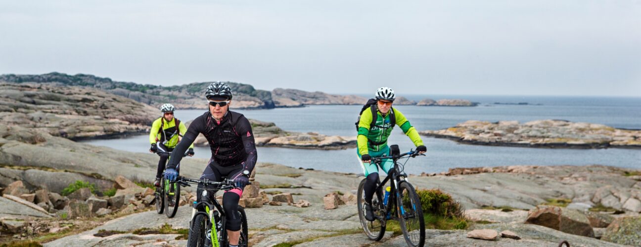 Tre cyklister på klippor.