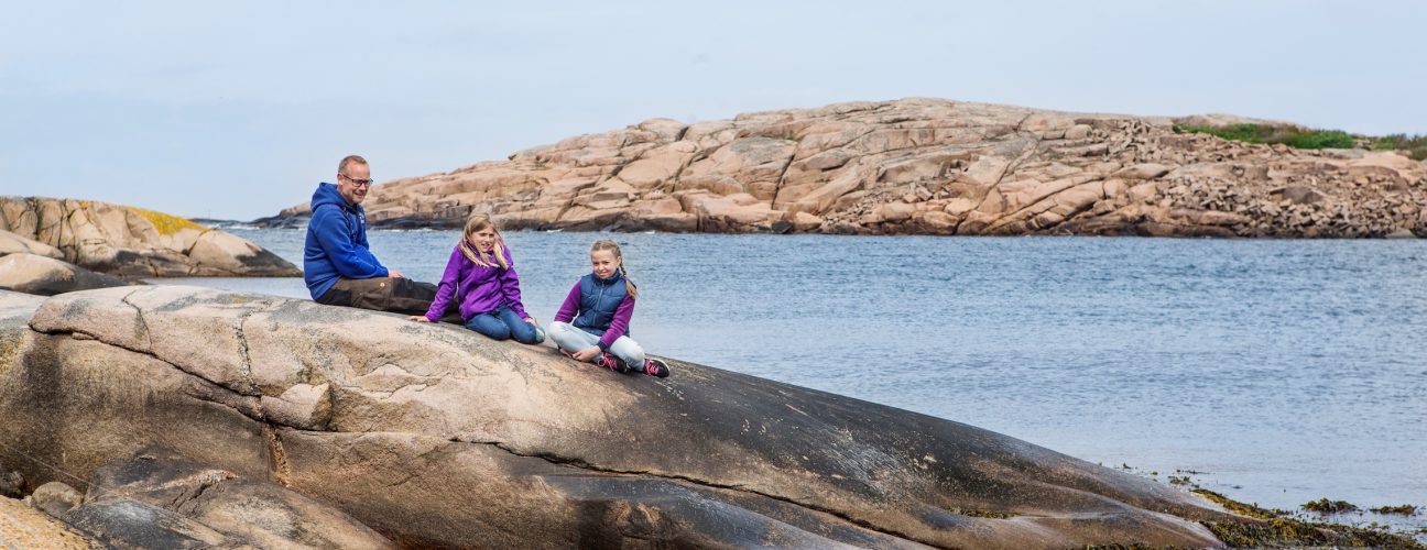 En familj som vilar på en klippa som sträcker sig ner i havet.
