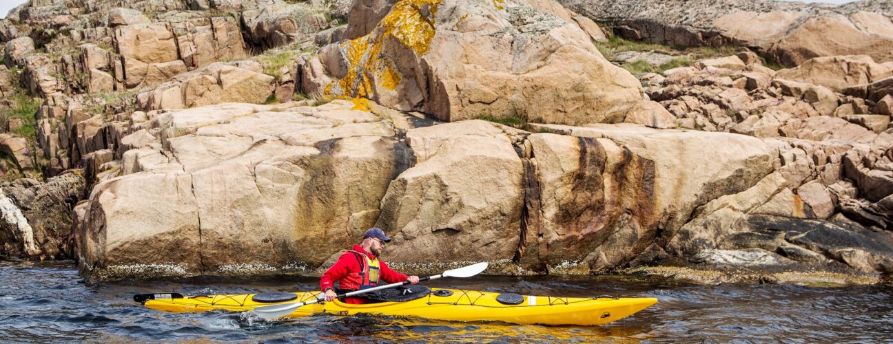 En man som paddlar kajak på Ramsvik, en outdoor-aktivitet där man får njuta av härligt friluftsliv