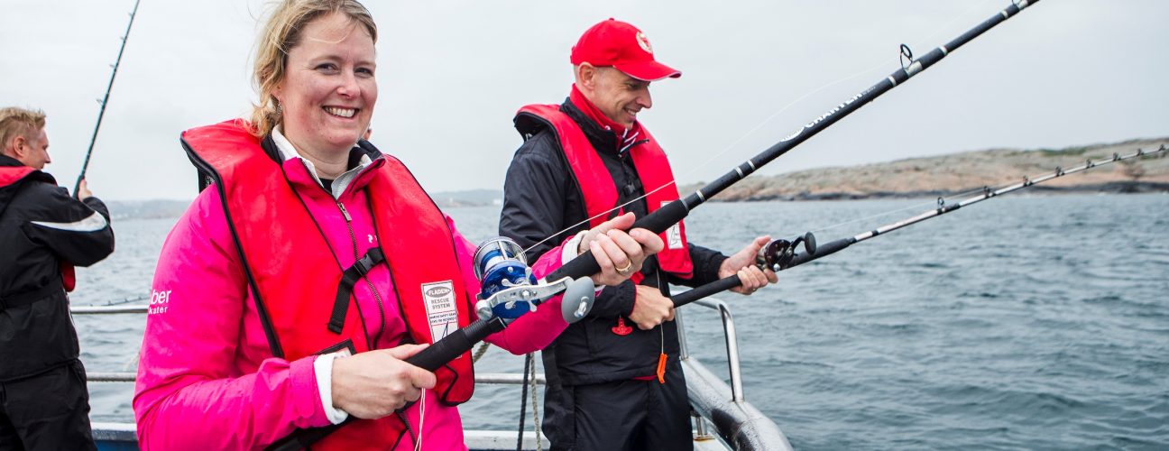 Tre glada personer som fiskar i en båt.