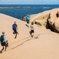 Ett gäng personer som har tagit del av Ramsvik vandringspaket och promenerar en solig dag.