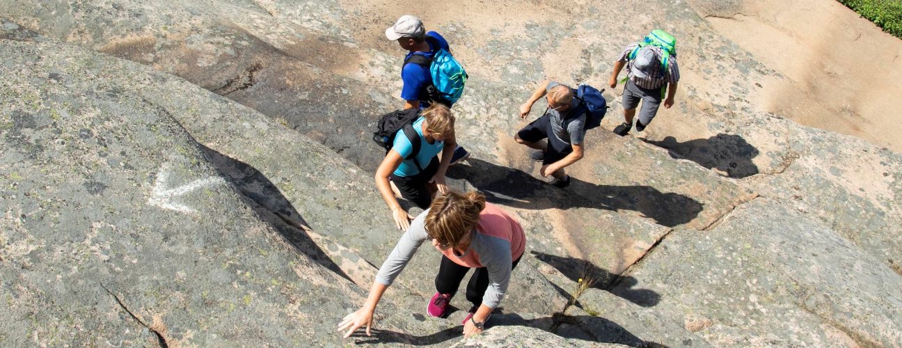 En familj som köpt Ramsvik vandringspaket, som tar sig upp för en klippa.