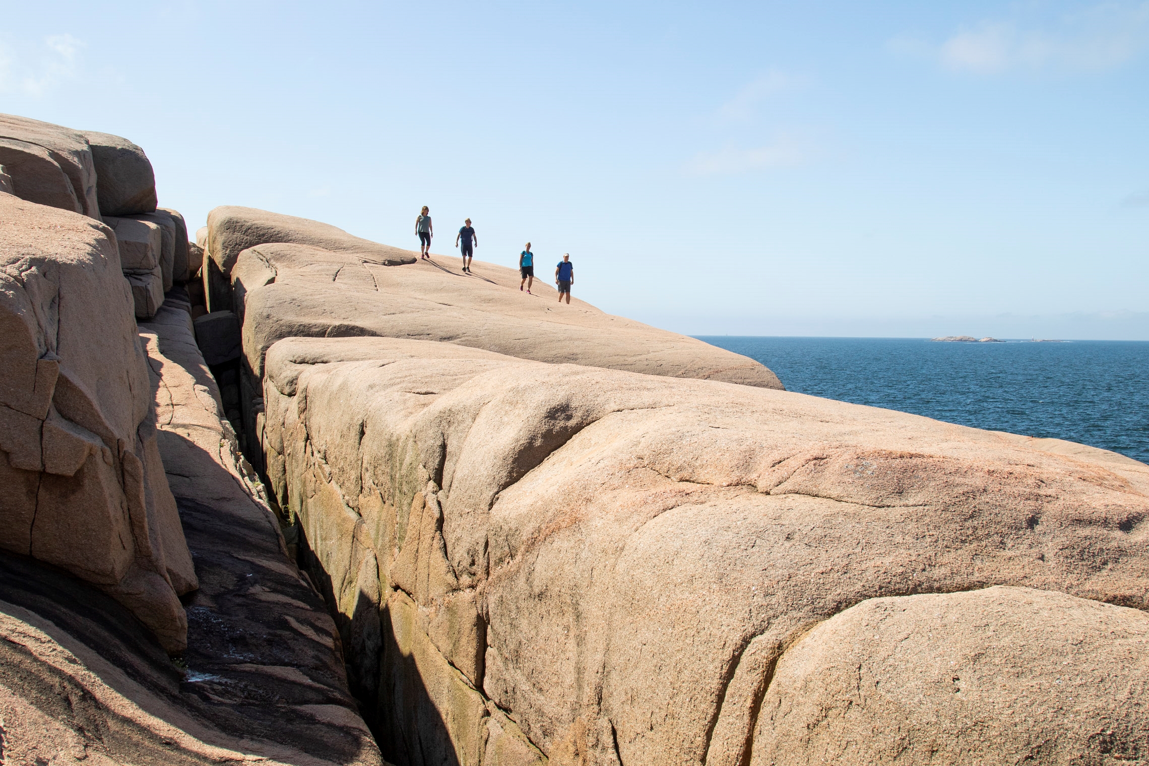 Vandring i Bohuslän med fyra person som promenerar på en klippa.