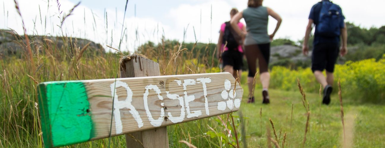 Närbild på en skylt som visar en vandringsled. Vandring i Bohuslän blir inte bättre än Ramsvikslandet.