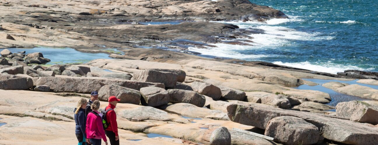 Tre personer som vandrar längs med klippor.