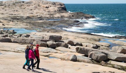 Tre personer som vandrar längs med klippor.