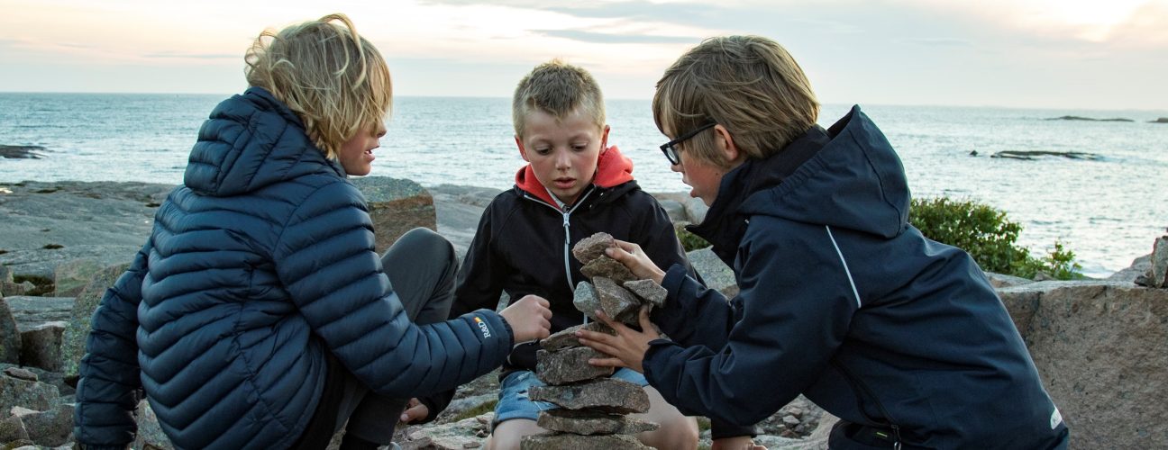 Tre personer som bygger en ett torn av stenar.