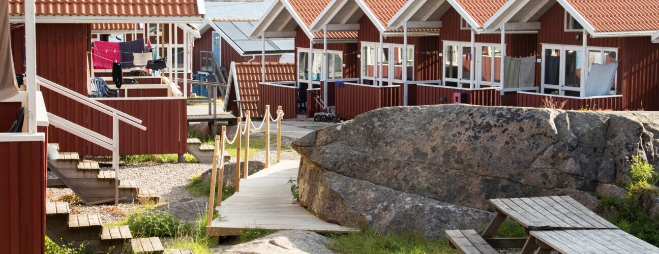 Flertalet röda stugor på Ramsvik Stugby & Camping på Smögen. En solig sommardag.