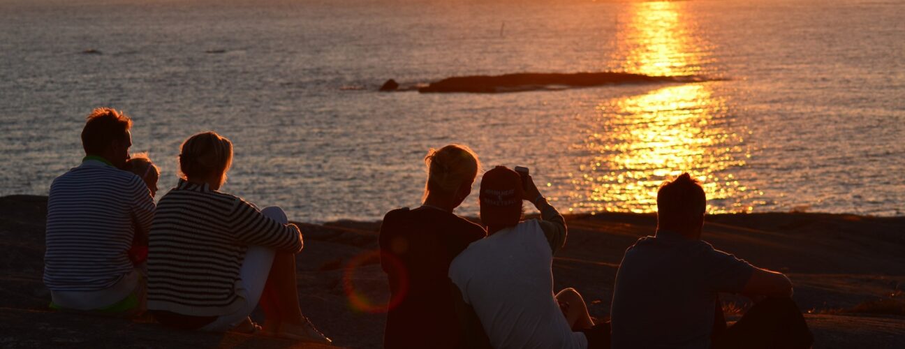 Familjekul med ett gäng människor som tittar på solnedgången.