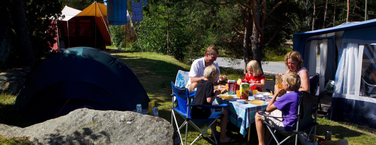 Familj som fikar bland husbilar och husvagnar.