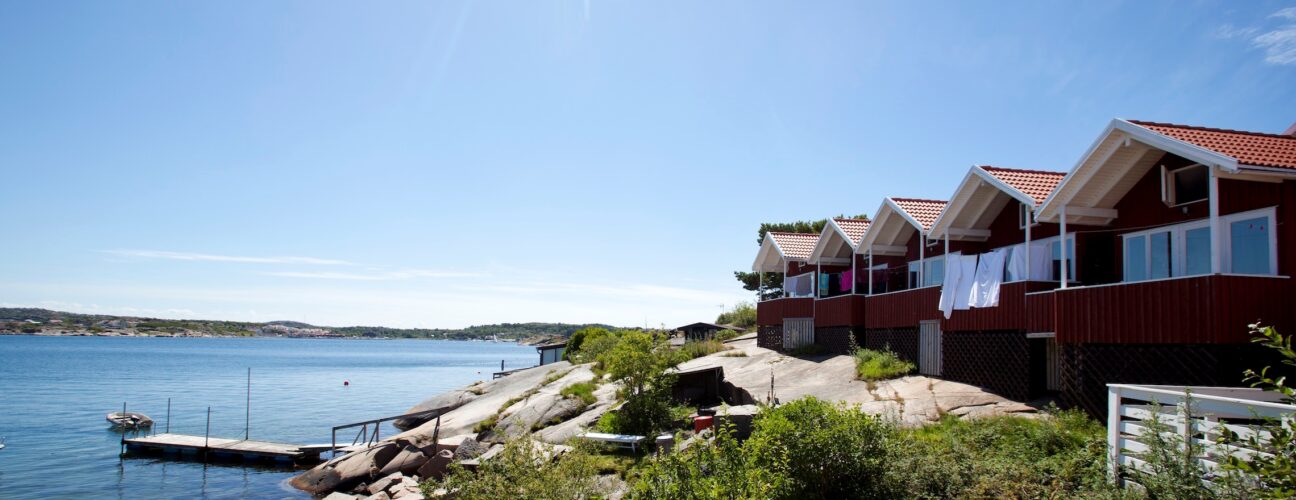 Solig bild på röda campingstugor i Bohuslän.