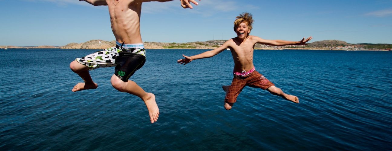 Två barn som hoppar ner i havet.