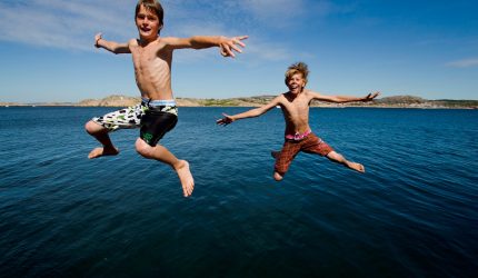 Två barn som hoppar ner i havet.