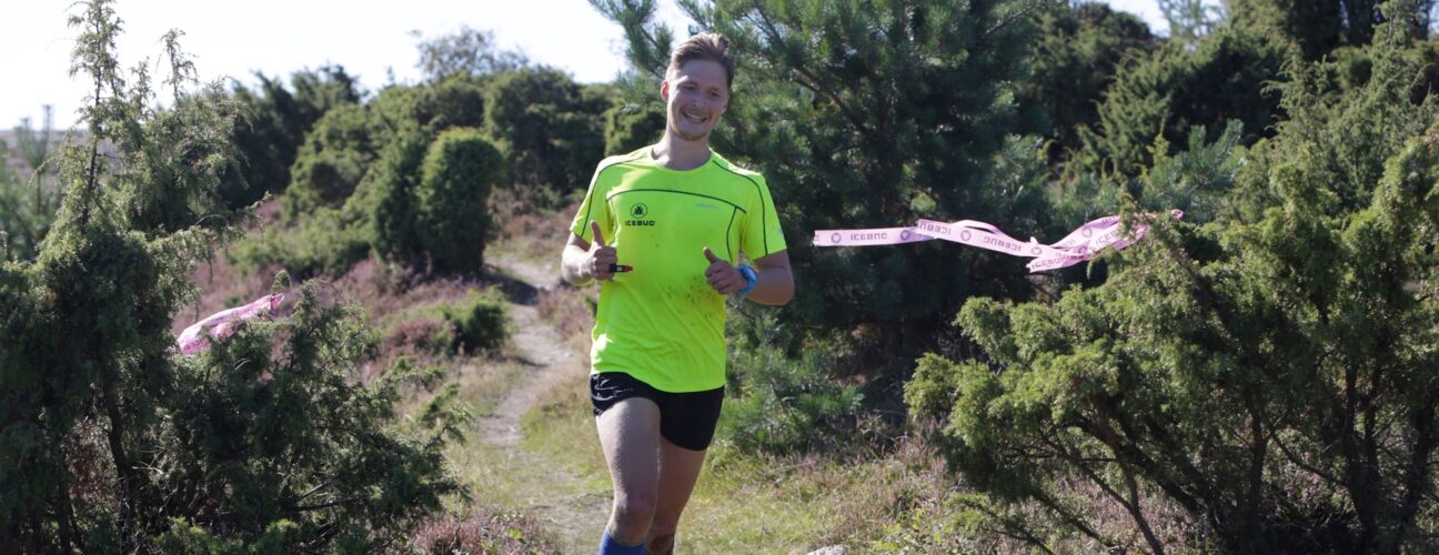 En man i en grön t-shirt som gör trailrunning.