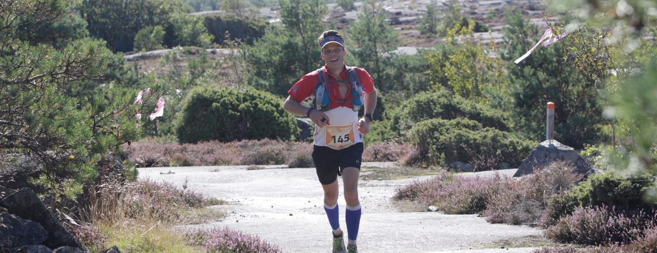 En man som springer i ett skogslandskap.