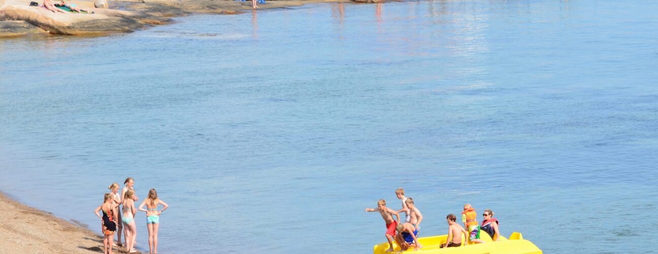 Barn som leker med en gul trampbåt i havet.